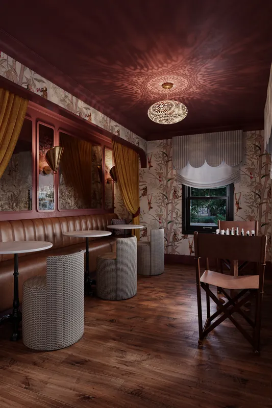 Hotel parlour with red walls, leather banquettes and patterned ceiling